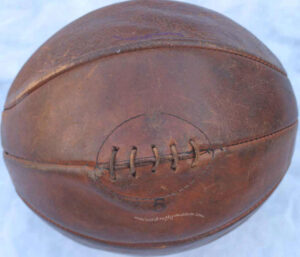 Rugby ball circa 1900. Quite round but slightly elongated. Pigs bladder wrapped in leather. Dark Tan colour